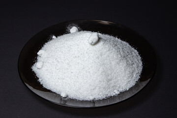 Heap of salt on a black background. Excessive salt intake. Coarse Rock salt