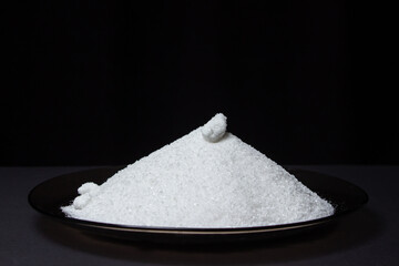 Heap of salt on a black background. Excessive salt intake. Coarse Rock salt