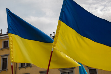 Ukrainian national flag on blue sky background. Protesters, holding Ukrainian flag, at...
