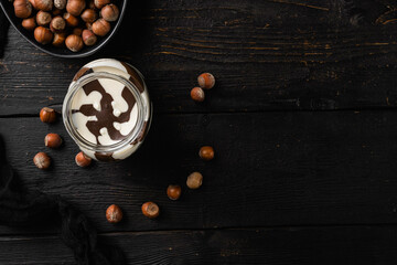 Hazelnut spread with nuts, on black wooden table background, top view flat lay, with copy space for text