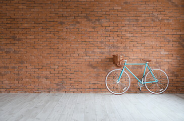 Modern bicycle near brick wall in empty room