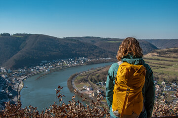 Obraz premium Hiker with backpack enjoys the view from the Teufelslay vantage point in the Moselle valley