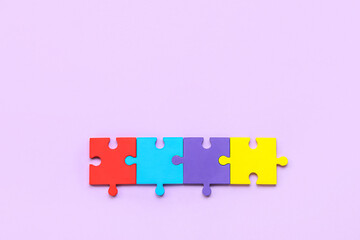 Colorful puzzle pieces on lilac background. Concept of autistic disorder