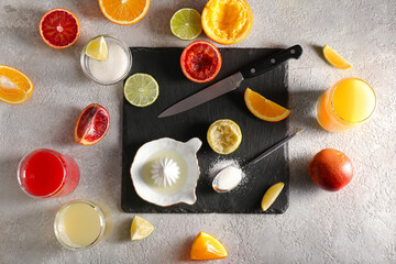 Ceramic juicer, juice, sugar and citrus fruits on grey background