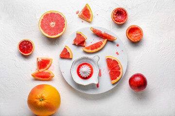 Ceramic juicer and grapefruits on light background