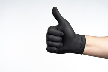 Gesture thumb up on white. Use of protective gloves. Man's hand makes class gesture. Concept of approving use of gloves. Man hand in black glove. Copy space on white. Thumb up is metaphor for praise
