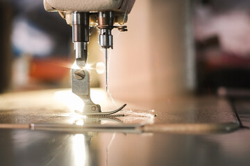 Industrial sewing machine for sew cloth with yellow light close-up.