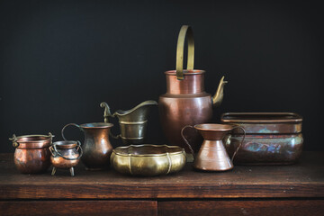 A collection of brass and copper dishes on a dark background