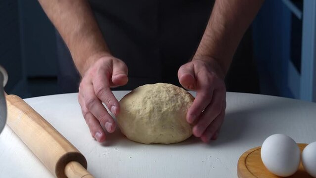 Chief raise up and throw pizza ball dought on wooden table. Filmed on black background