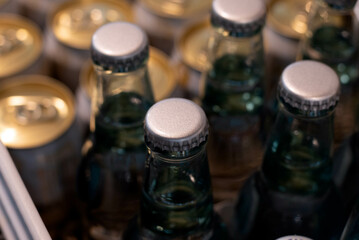 Aluminum crown caps on glass beverage bottles at a grocery or supermarket.  - obrazy, fototapety, plakaty