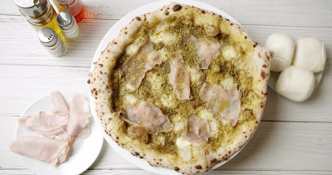 Pizza with Meat, Pesto, Cheese and Parmesan fresh out of the oven ready to eat. Delicious Italian pizza. Napoli Pizza. Food Service on white table and ingredient. Tasty Pizza with Cheese and Parmesan.