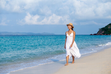 Fototapeta na wymiar A happy traveling girl in white dress is walking enjoying on summer vacation on tropical beach at Koh Larn island Pattaya, Thailand