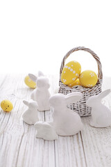 basket with colorful easter eggs on white rustic wooden background
