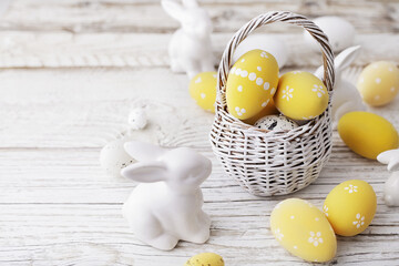 basket with colorful easter eggs on white rustic wooden background