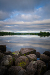 Clouds reflect on a lake with large rocks in the foreground
