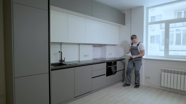 The builder checks the quality of the installation of kitchen furniture construction