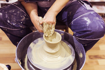 Fototapeta premium Woman Pottery Artist. Workshop Molding Clay On Pottery Wheel. Ceramic Studio. Closeup View On Female Hands.