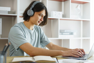 Distance education concept, Teen boy wear headphone to lesson class online and type chat in skype