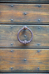 Antique wooden door with rusty iron round knocker