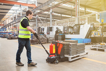 Warehouse worker dragging hand pallet truck or manual forklift with the shipment pallet unloading...
