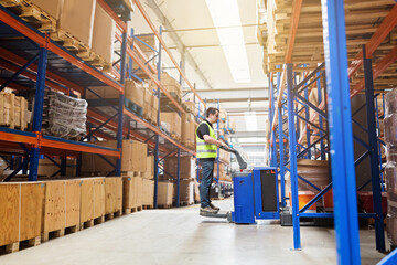 Storehouse employee in uniform working on forklift in modern automatic warehouse. Boxes are on the shelves of the warehouse. Warehousing, machinery concept. Logistics in stock.