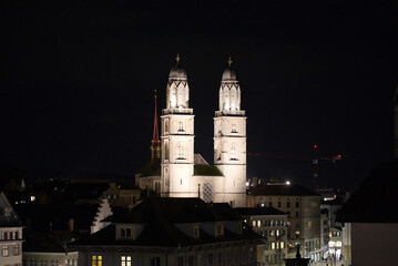 Naklejka premium Illuminated protestant church Great Minster at the old town of Zürich on a winter night. Photo taken February 24th, 2022, Zurich, Switzerland.