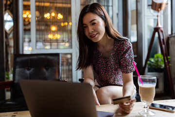 Pretty young asian business woman using laptop in modern cafe. 
