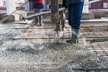 Builders workers pour concrete floor in industrial workshop. Legs in boots in concrete. Submission...