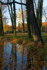 Historyczny park pałacowy jesienią z widocznymi budynkami mieszkalnymi i gospodarczymi. - obrazy, fototapety, plakaty
