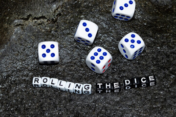 Mote alphabet blocks arranged into "rolling the dice" and five dice on a rock.