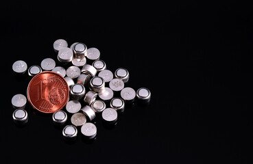 One cent euro coin surrounded by small button cell batteries