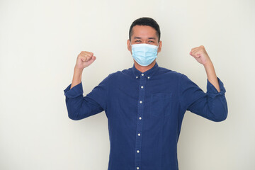 Adult Asian man wearing medical mask showing his bicep muscle. Health concept