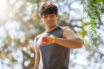 Young man doing sports look at the smart watch and laugh in the park