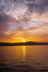 Fototapeta na wymiar Sunrise in the seaside. Reflection of boats, walking people, fishermen