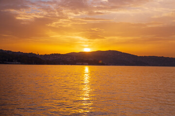 Sunrise in the seaside. Reflection of boats, walking people, fishermen