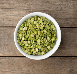 Raw dried green peas in a bowl over wooden table