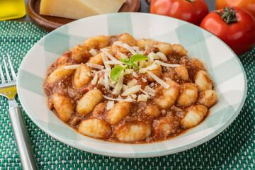 Italian pasta gnocchi on a plate with bolognese sauce, basil and parmesan cheese