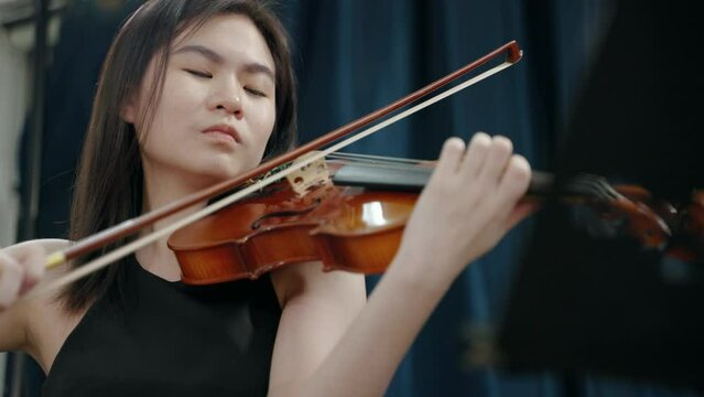 Young Asian woman playing violin at a festival party
