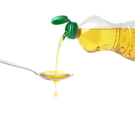 Pouring cooking oil from plastic bottle into spoon isolated on white background.