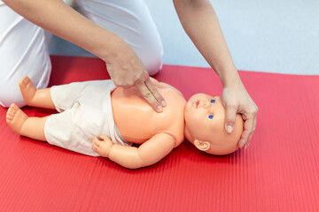 Woman performing CPR on baby training doll with one hand compression. First Aid Training -...