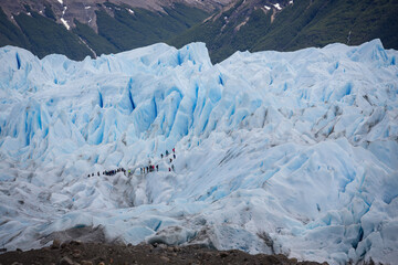 Eine Gruppe von Menschen überquert die Gletscherzunge des Perito Moreno Gletschers und passiert...