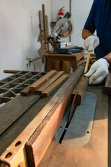 A carpenter working on sawing wood to make furniture in a studio. Soft focus