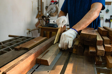 A carpenter working on sawing wood to make furniture in a studio. Soft focus