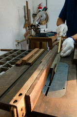 A carpenter working on sawing wood to make furniture in a studio. Soft focus