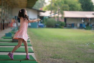 young girl practices her golf swing on driving range