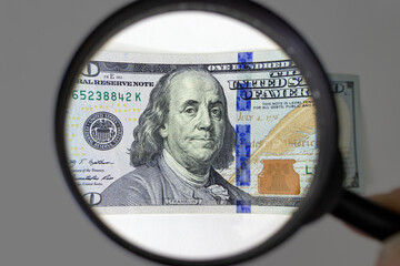 Magnifying glass on dollar banknotes. Checking suspicious money of magnifying glass.