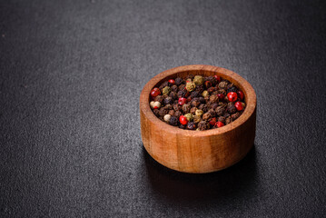 Black, red and white pepper in bowl on f black concrete background