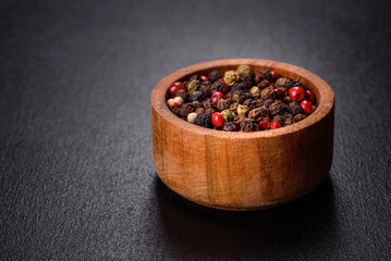 Black, red and white pepper in bowl on f black concrete background