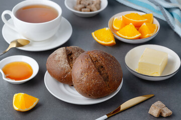 Rye buns and breakfast butter with tea and orange