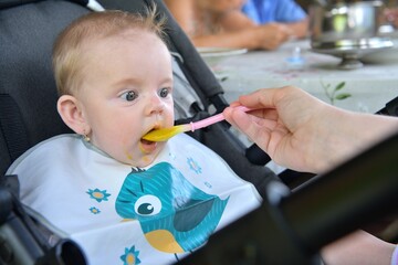 Portrait of a baby's mouth being fed baby gruel 